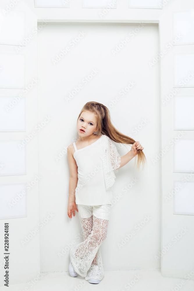 Cute little blond girl wearing white casual clothes on a white background. Fashion style. Cute little blond girl wearing white casual clothes on a white background. Fashion style.