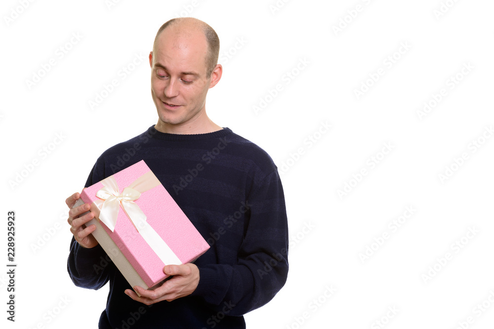 Happy bald Caucasian man smiling while holding and looking at gi Happy bald Caucasian man smiling while holding and looking at gi