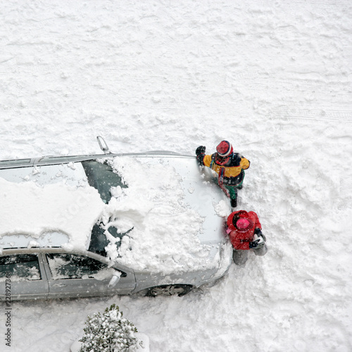 Children play in snow around cars in parking lot
