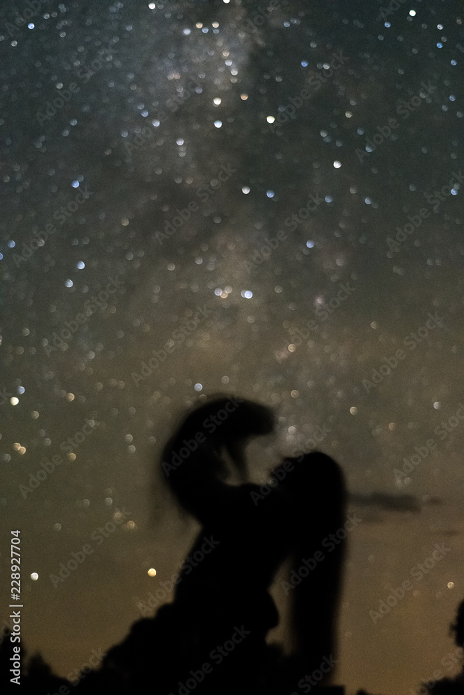 Silhouettes of a girl with a cat couples against the milky way