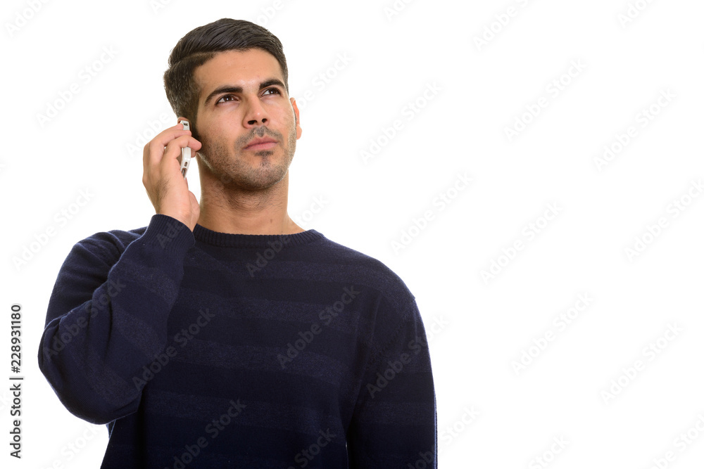 Young handsome Persian man talking on mobile phone while thinkin Young handsome Persian man talking on mobile phone while thinkin