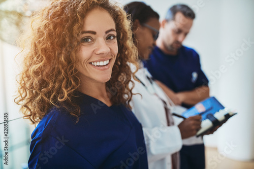 Smiling young medical intern standing with doctors in a hospital