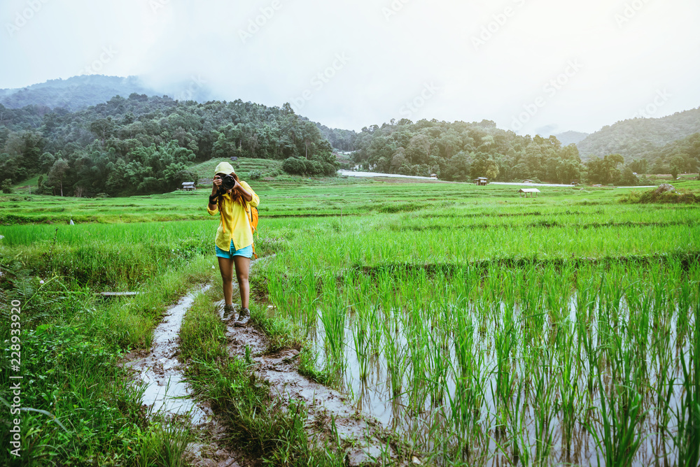 Asian woman travel nature Travel relax Walking take a photo on the rice field in rainy season.