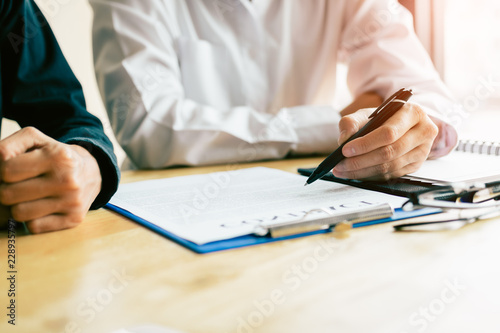 Man signing a contract with financial advisor on desk.