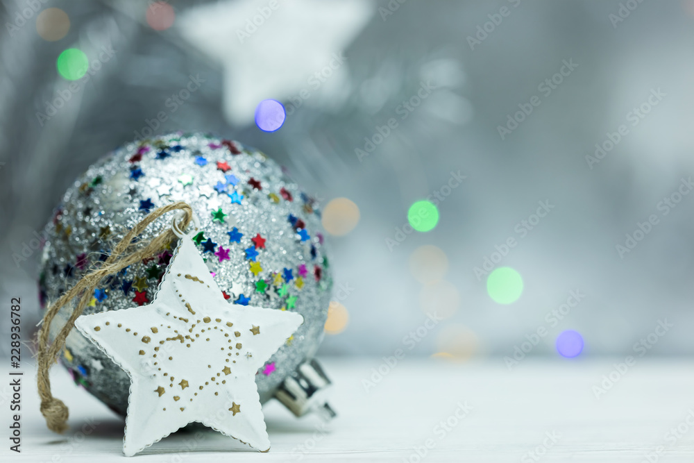 bright christmas ball and star decoration on defocused grey background with blurred lights