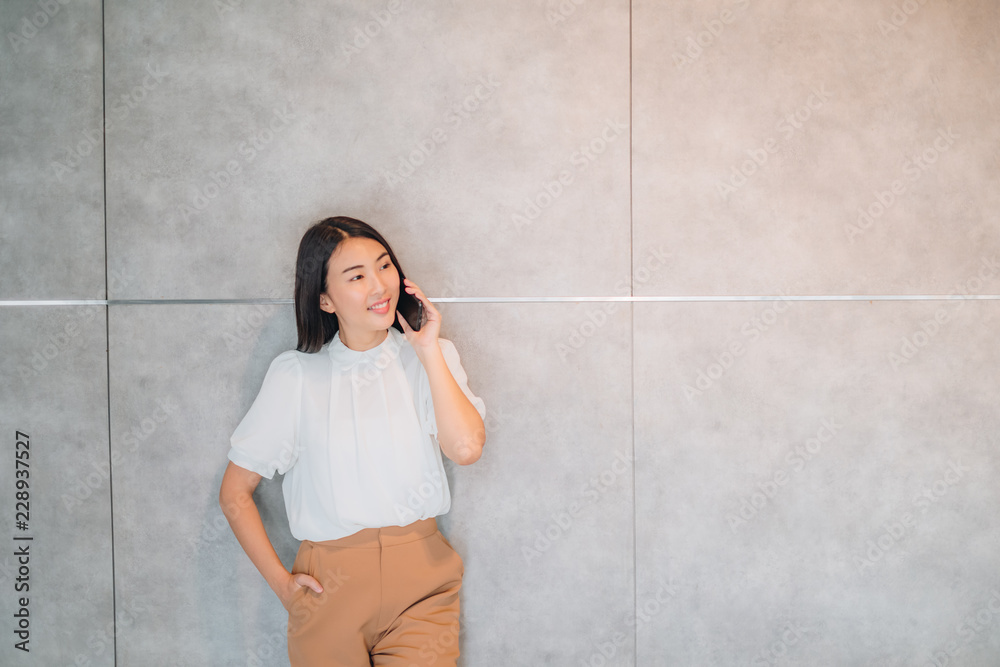 Cheerful young Asian beautiful woman long black hair with brown suit cloth talking on mobile phone with client. Happiness time after work Cheerful young Asian beautiful woman long black hair with brown suit cloth talking on mobile phone with client. Happiness time after work