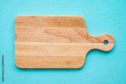 Top view of unused brand new brown handmade wooden cutting board on blue wooden table background