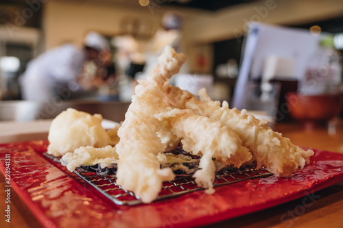 Delicious shrimp in tempura with the blurred background, chef in the kitchen and japanese style counter bar