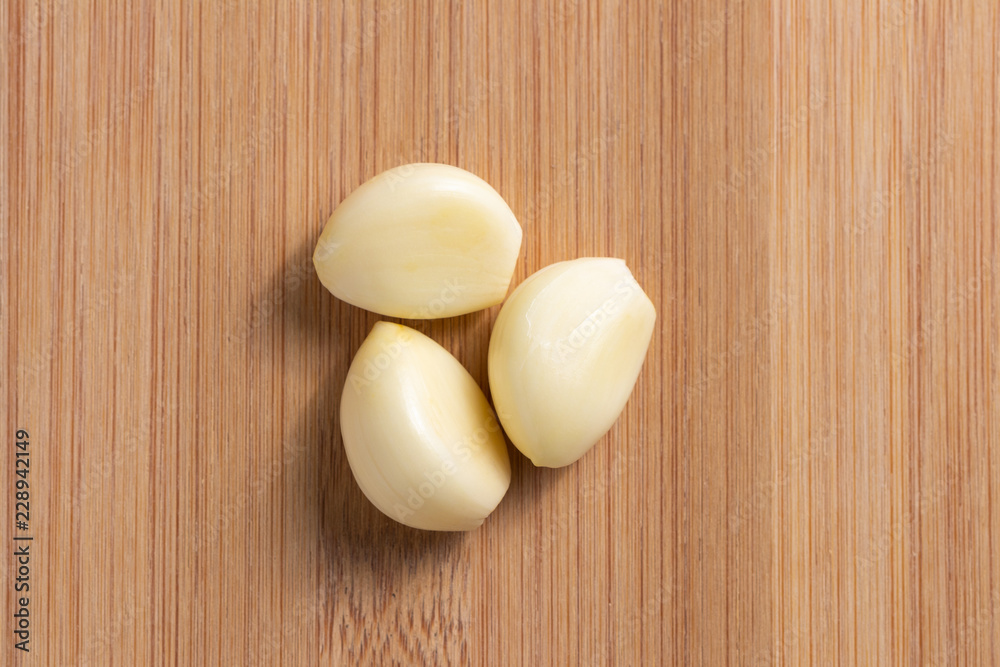 Peeled garlic on wooden plate in the middle. Top view Peeled garlic on wooden plate in the middle. Top view