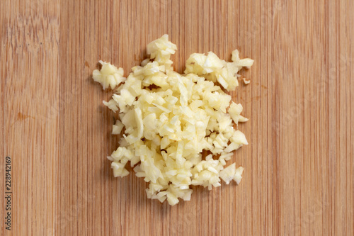 Bild auf Leinwand Garlic minced on wooden plate in the middle. Top view