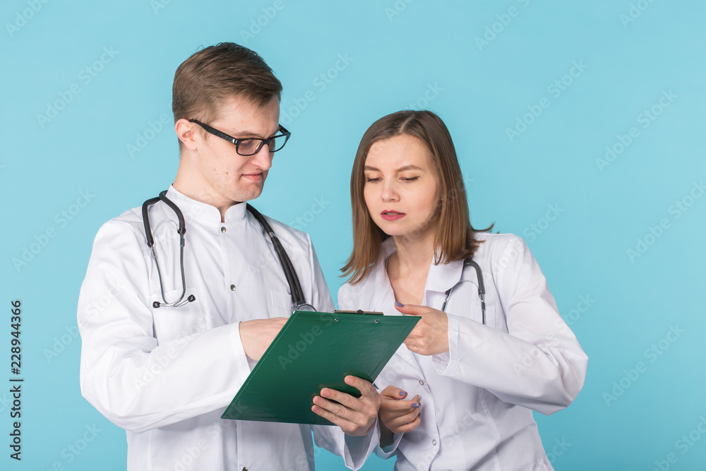 Young male and female doctors discussing in blue background Young male and female doctors discussing in blue background