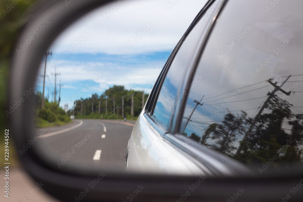 Naklejka premium Image reflected from the mirror of the car. See the road and the sky And trees along the way.