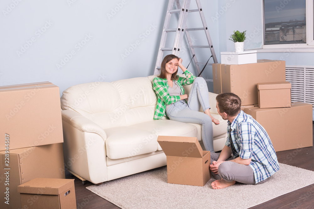 Moving, new apartment and relocation concept - young couple in the room surrounded by boxes having a small talk. Moving, new apartment and relocation concept - young couple in the room surrounded by boxes having a small talk.