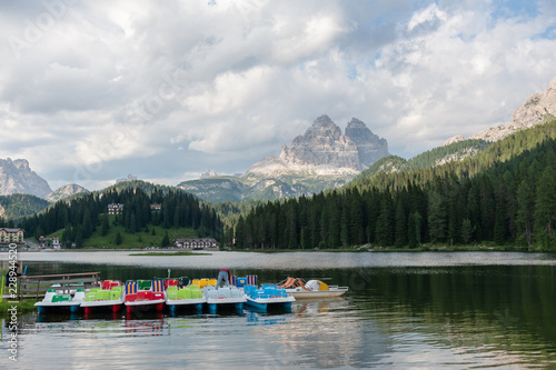 Elderly couple tending to the boats, at the end of a summer's day, on lake Misurina, in the Italian Alps, surrounded by imposing mountains. Italian Dolomites, summer of 2018.