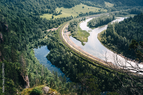 Railway near the river. Summer forest in the park