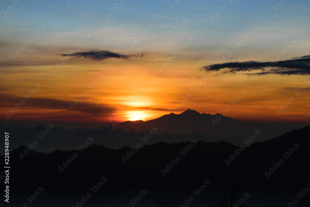 Early sunrise view from Gunung Batur volcano in Bali with visible silhouette of Rinjani mountains