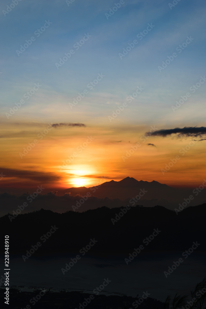 Early sunrise view from Gunung Batur volcano in Bali with visible silhouette of Rinjani mountains