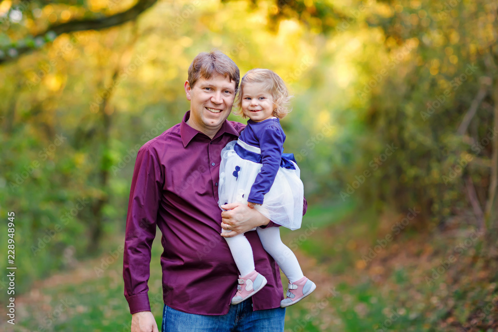Fototapeta premium Happy young father having fun cute toddler daughter, family portrait together. man with beautiful baby girl in nature and forest. Dad with little child outdoors, hugging. Love, bonding.