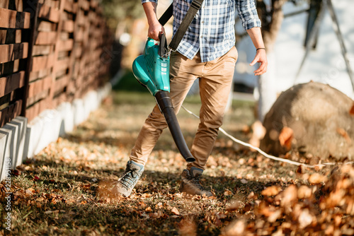 Gardening details - professional landscaper using leaf blower photo