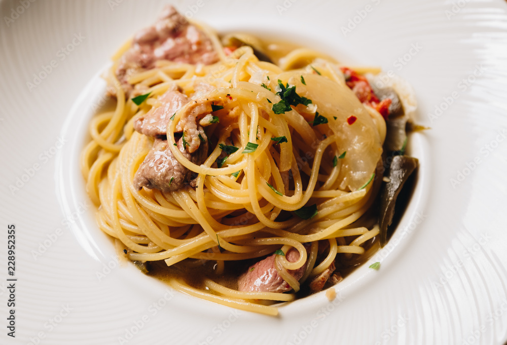 Spaghetti spicy with bacon, dry chili, green olive in white dish top view on wooden background. Spaghetti spicy with bacon, dry chili, green olive in white dish top view on wooden background.