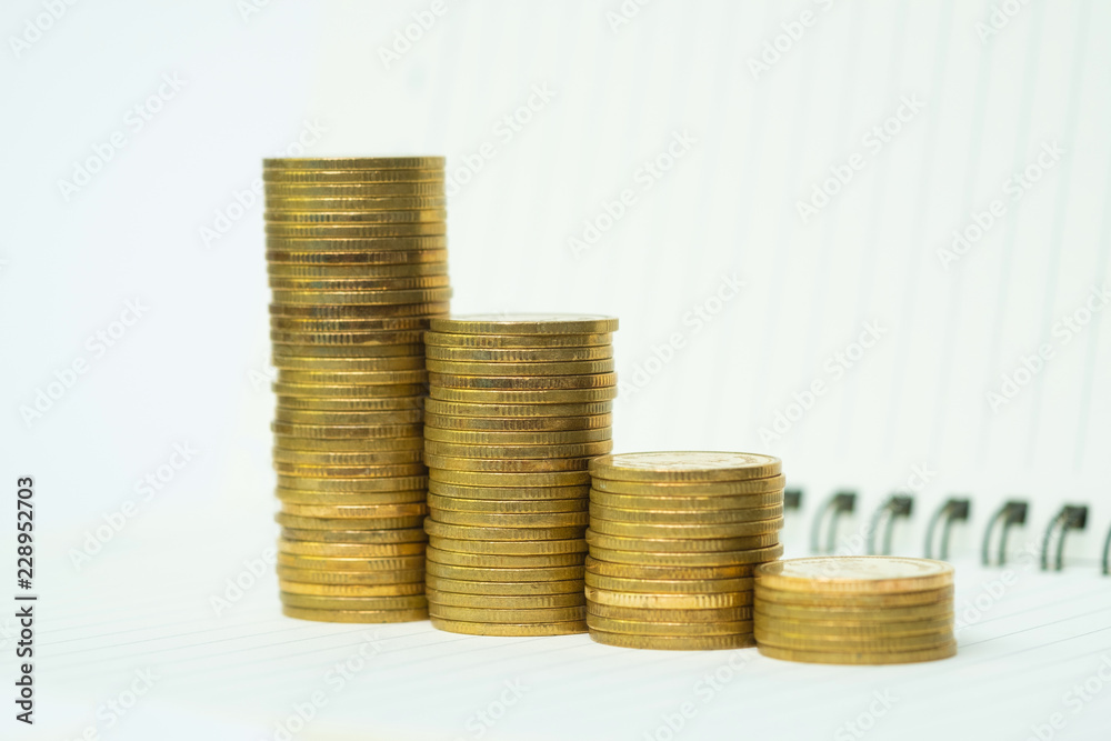 Step of coins stack on notebook paper with copy space for add text, financial and business planning concept. Step of coins stack on notebook paper with copy space for add text, financial and business planning concept.