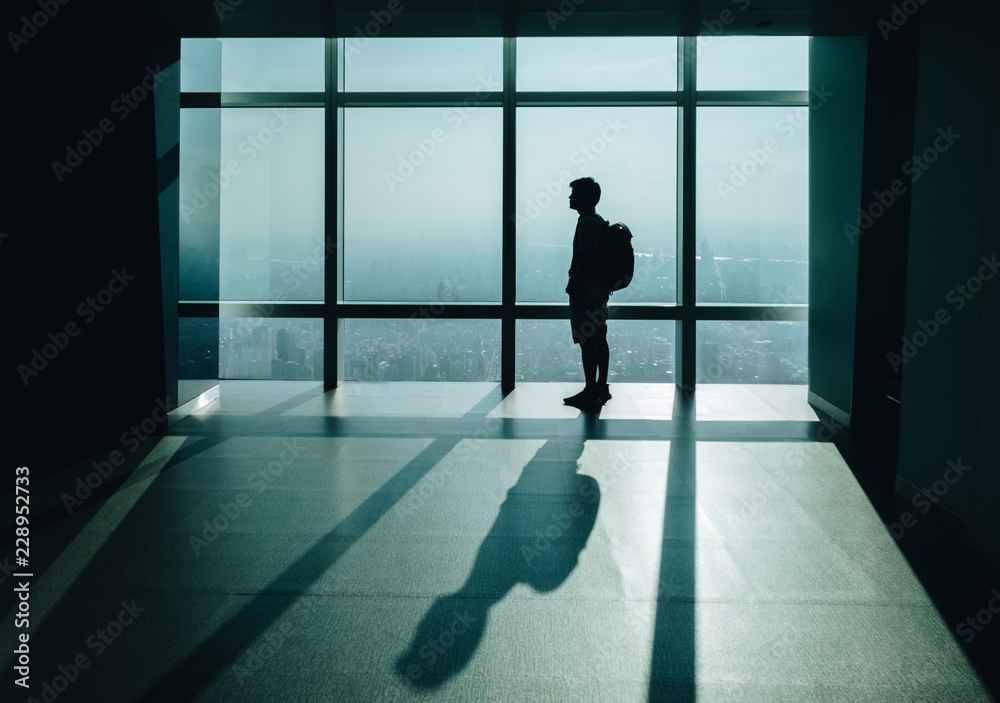 Fototapeta premium Silhouette of man,he is Looking ahead outside of building.