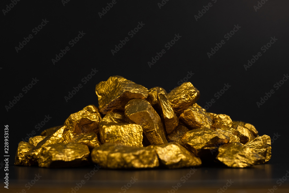 Fototapeta premium A pile of gold nuggets or gold ore on black background, precious stone or lump of golden stone, financial and business concept.