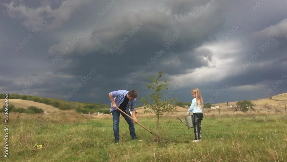 Father and daughter plant a tree seedling in a the garden. Friendly family. Father and daughter plant a tree seedling in a the garden. Friendly family.