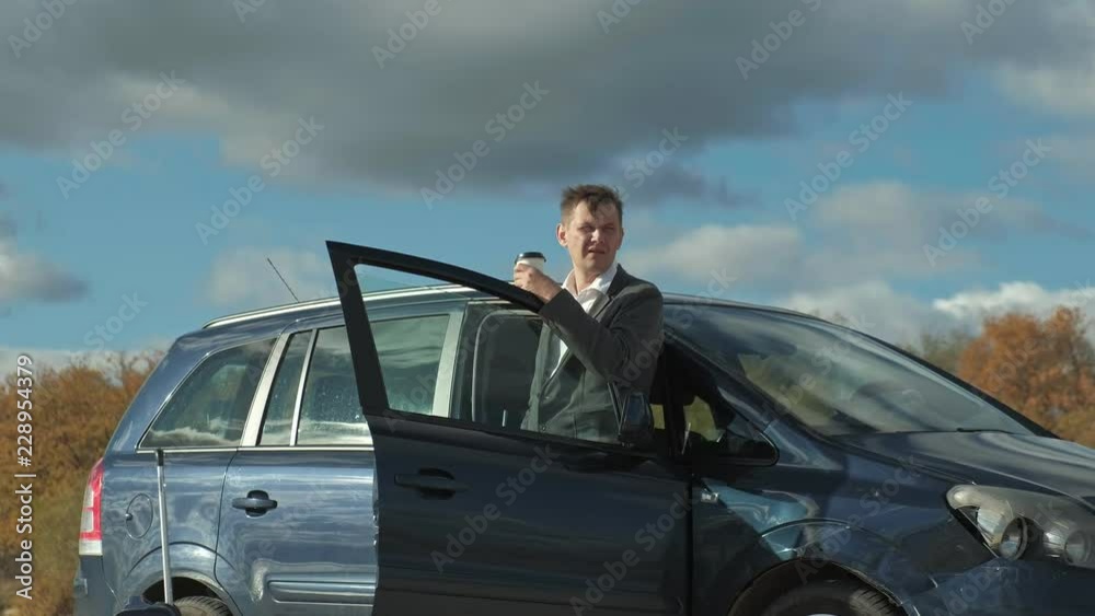 Businessman with a laptop suitcase working relaxing on the beach near his car.