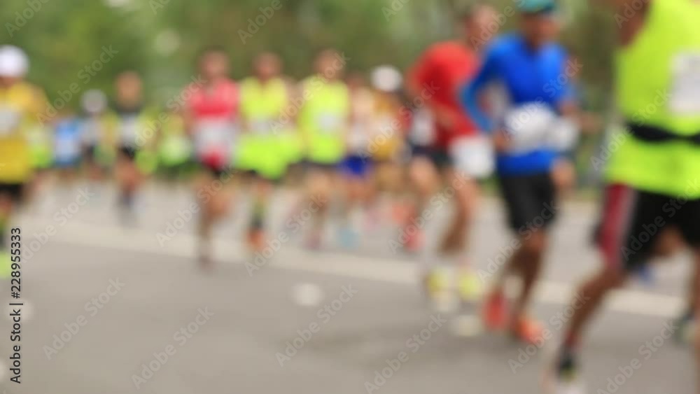 Defocused marathon runners running on city road Defocused marathon runners running on city road
