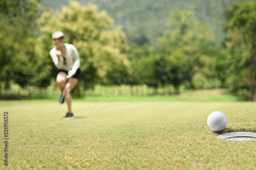 Woman golfer cheering after a golf ball on a golf green