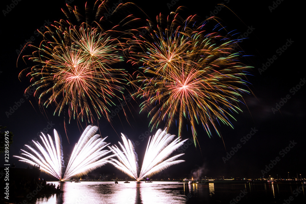 Fantastic simultanious giant fireworks explosions in the night over lake Fantastic simultanious giant fireworks explosions in the night over lake