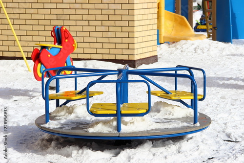 Blue carousel on  Modern new beautiful Playground in winter snowy day - children leisure on the outdoor photo