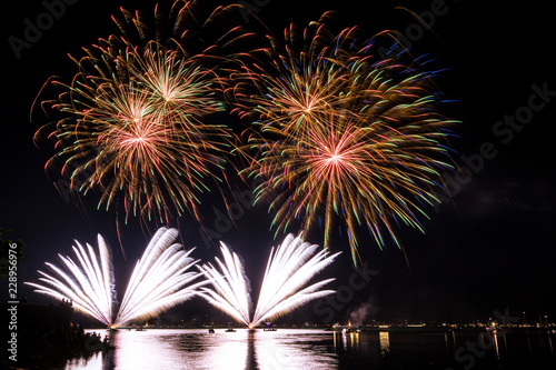 Fantastic simultanious giant fireworks explosions in the night over lake