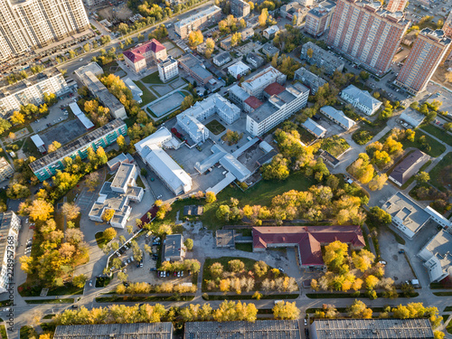 Aerial view of a large number of residential buildings on the outskirts of the city on an autumn day during the Indian summer with the road and cars