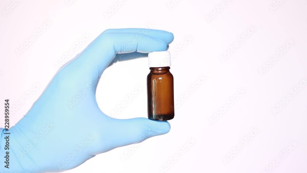 Hand in latex glove holding vial with medicine Hand in latex glove holding vial with medicine