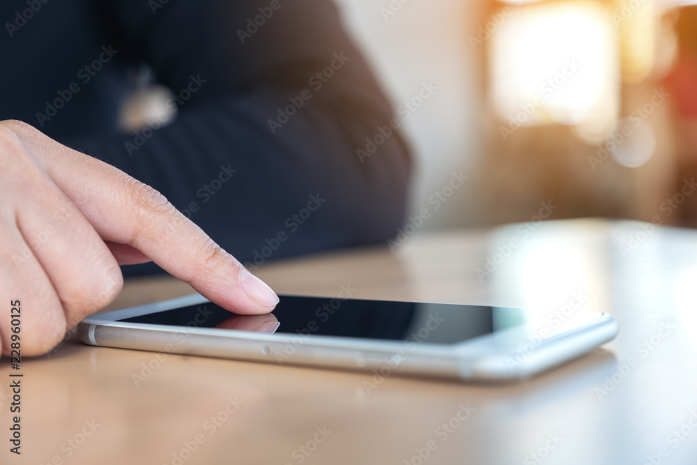 A woman using and touching smart phone on wooden table with blur background A woman using and touching smart phone on wooden table with blur background