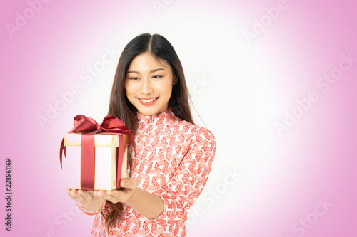 Photo of asian curious woman in red dress rejoicing her birthday or new year gift box. Young woman holding gift box with red bow being excited and surprised holiday present isolated white background