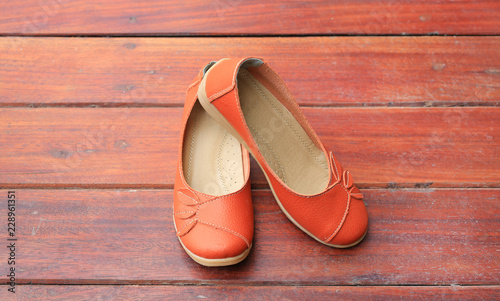 Orange leather female shoes on wood