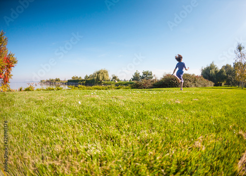 A girl in a dress runs through a green meadow.