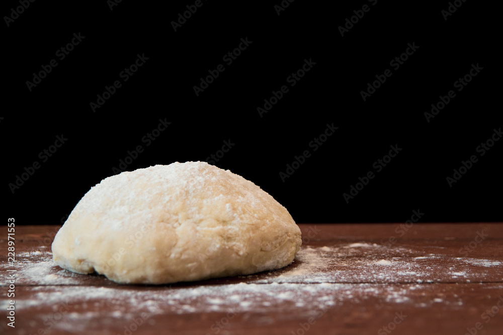 a lump of dough lie on a wooden table on a black background a lump of dough lie on a wooden table on a black background