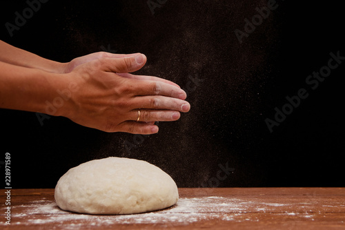 a lump of dough lie on a wooden table on a black background
