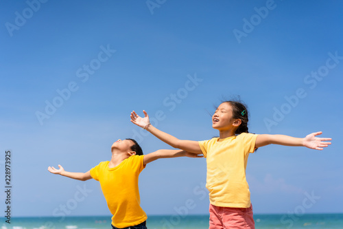 Asian children relaxing on the beach with blue sky and beautiful sea background