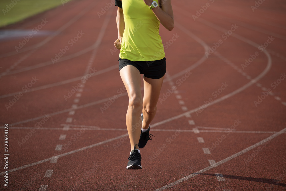 Fitness sportswoman running on stadium tracks