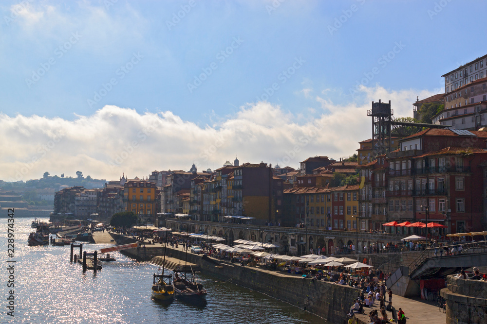View of Ribeira, Porto, Portugal. Embankment of river Douro in a summer sunny day. Boats at the pier. Popular tourists destination.