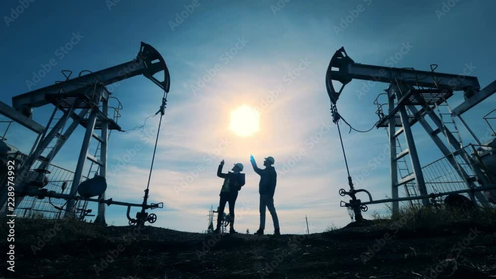 Engineers look at oil pumps working. Oil rigs pumping.