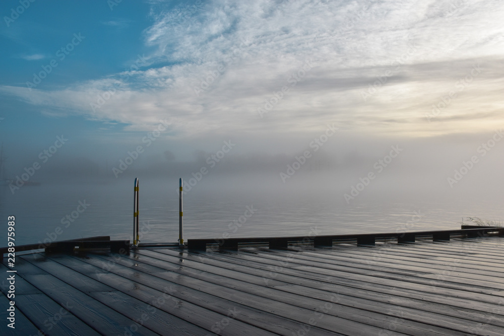 Stairway into the water. Smooth staircase into the water. Morning fog on the lake, sunrise shot. Magical morning fog. Wooden pier. Oslo, Norway