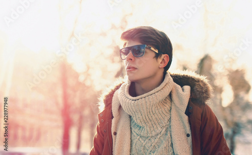 Fashion portrait man in sunglasses walking in sunny evening city