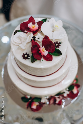 wedding cake with decorated with red and white orchid petals