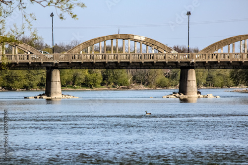 Obraz na płótnie Looking Down the Grand River in Caledonia Ontario, Canada at a Concrete Car Bridge Crossing Shore to Shore. w salonie